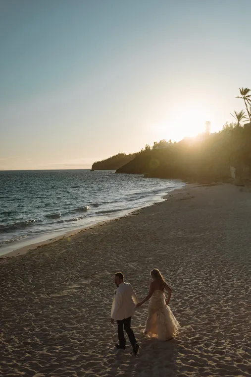 Two small figures on an empty beach at sunset